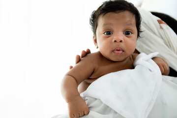 Happy three month old African American baby boy lying on her shoulder mothers. Portrait of a cute little smiling baby on mother's shoulder, happy african american family isolated on white background,