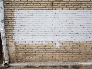  On a brown brick wall with a downpipe, the central rectangular part was painted over with white paint.