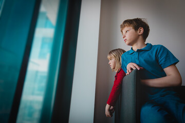 Wall Mural - boy and girl staying home due to social distancing, kids looking at the window