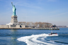 Statue Of Liberty In NY Harbor With Racing US Coast Guard Patrol Boat, Blue Sky And Water