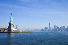 Statue Of Liberty In NY Harbor On Bright Sunny Day With Blue Sky And Manhattan In The Distance