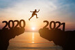 © Dilok - Happy new year 2021 and silhouette concept , Man jumping from 2020 to 2021 with beautiful orange sky and sea.