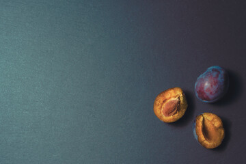 three ripe plums on a kitchen stone table close up