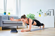 © Bartek Szewczyk/Westend61 - Woman extending arm during plank pose while learning exercise on internet through tablet PC