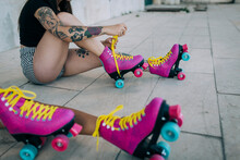 Low Section Of Friends With Roller Skates Sitting On Footpath