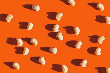 raw round pasta on a bright orange background. Food pattern