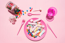Studio Shot Of Glass Of Water, Jar Of Candies And Plastic Plate Filled With Various Sweets