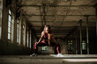 © Gala Mart√≠nez L√≥pez/Westend61 - Woman with hand on knee crouching at abandoned factory