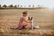 Woman Enjoying With Border Collie Dog In Wheat Field During Sunset