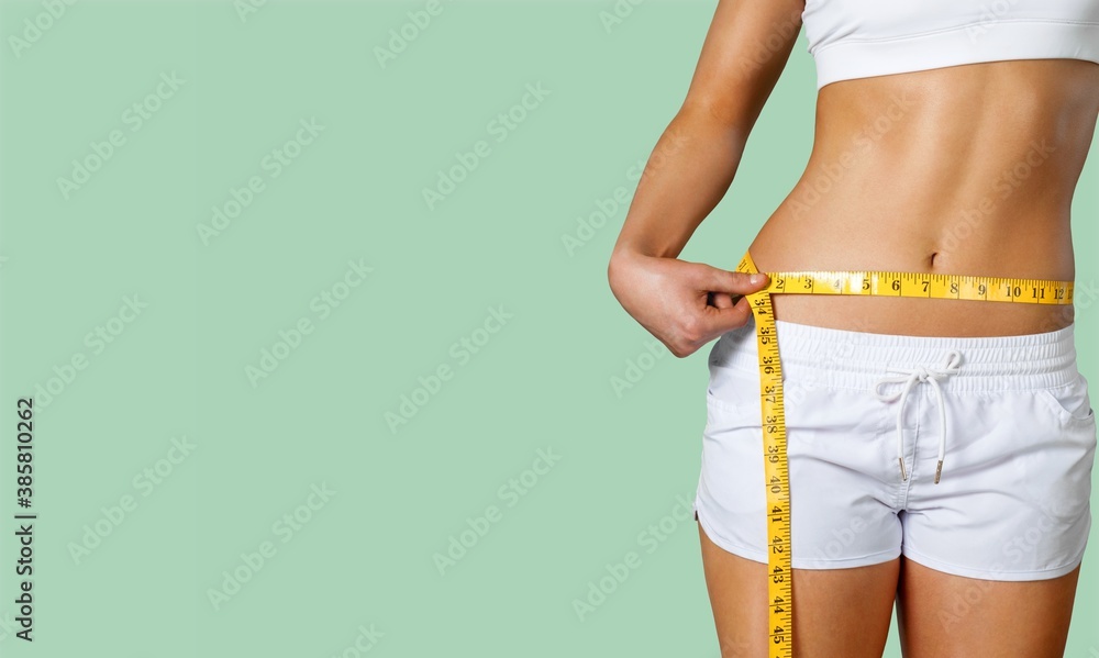 Slim young woman measuring her thin waist with a tape measure - obrazy, fototapety, plakaty 