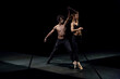 © Nadine Ginzel/Westend61 - Male and femal dancer performing contemporary ballet on black stage