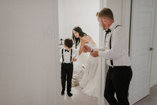 Mother Dressing Son For Wedding While Father Standing In Doorway At Home