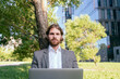 © Vasily Pindyurin/Westend61 - Confident handsome businessman sitting with laptop against tree at financial district