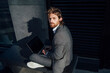 © Vasily Pindyurin/Westend61 - Confident young businessman with laptop sitting on bench at financial district in city