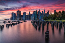 Scenic View Of Mooring Posts In East River With Lower Manhattan Skyline In Background During Sunset