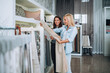 © hedgehog94 - Young woman designer talking with a saleswoman and chooses fabrics for curtains in textile show room.