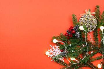 Wall Mural - christmas background with branches and decorations on a red table.