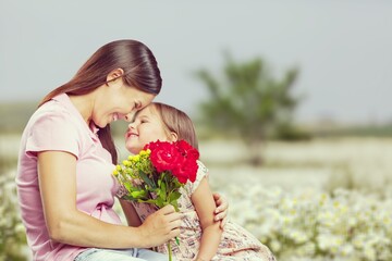 Wall Mural - Happy beautiful mother and daughter hugging with a bouquet