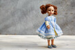 © Татьяна Кутина - doll in a yellow and blue dress, on a gray concrete background. copy space