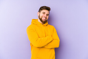 Wall Mural - Young man isolated on purple background who feels confident, crossing arms with determination.