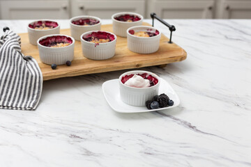 Wall Mural - White Ramekins of Blueberry and Blackberry Cobbler on a Wooden Tray; One Isolated in Front; Kitchen Countertop