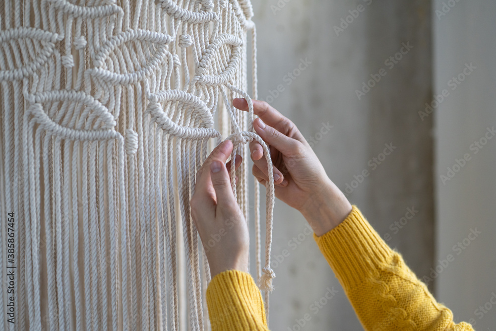 Close up of freelancer woman working on half-finished macrame piece, weaves lamp shade for chandelier. Women hobby. - obrazy, fototapety, plakaty 