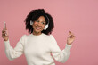 © DimaBerlin - Happy dark skinned millennial woman with headphones enjoying listening to the artist's new album, dances, makes movements to music, holding mobile phone, isolated on studio pink background. Copy space