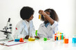 © Art_Photo - Two african american cute little boy and girl student child learning research and doing a chemical experiment while making analyzing and mixing liquid in test tube at science class on the table