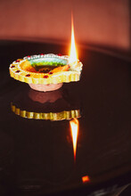 A Glowing Diya With Its Reflection In The Mirror For Diwali Celebration