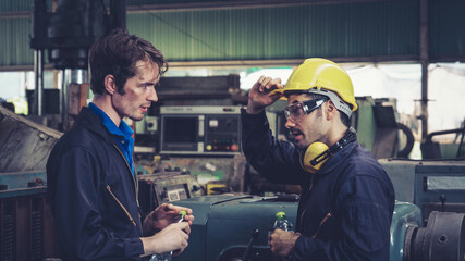 Tired factory workers taking a break and talking to coworker in the factory . Industry and engineering concept .