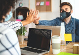 Fototapeta  - Young people in co-working creative space wearing surgical mask protection and keeping social distance to avoid corona virus spread - Health care and business technology concept