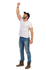 Wall Mural - Young Casual Man In Black Cap Is Standing With Arm Raised, Shouting And Looking Up