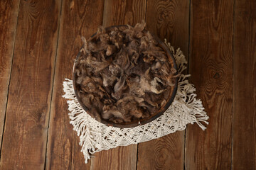 Newborn photography digital background prop. wicker basket with brown fur on a wooden background.