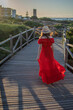 © josehidalgo87 - a female model in a red dress walking down a windy wooden pathway during sunrise