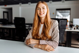 Fototapeta  - Smiling business young woman sitting at work desk in office