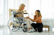 © ake - caucasian senior patient recover woman on wheelchair and mixed race daughter in hospital room new normal.