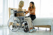 © ake - caucasian senior patient recover woman on wheelchair and mixed race daughter in hospital room new normal.