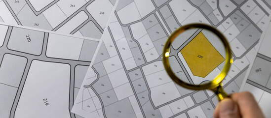 Wall Mural - hand with magnifier on cadastre map - search and buy land concept. banner copy space