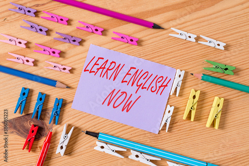 Text sign showing Learn English Now. Business photo text gain or acquire knowledge and skill of English language Colored clothespin papers empty reminder wooden floor background office