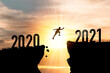 Welcome merry Christmas and happy new year in 2021,Silhouette Man jumping from 2020 cliff to 2021 cliff with cloud sky and sunlight.