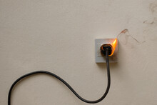 On Fire Electric Wire Plug Receptacle On The Concrete Wall Background