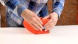 © markwar - Gift making industry. Female well-groomed hands correctly pack a box with a gift in red wrapping paper. Gift box for Christmas or New year. Woman in shirt wrapping a birthday present or surprise box.