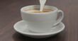 © GCapture - pour steamed milk into cappuccino white cup on walnut table