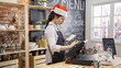 © PRPicturesProduction - waitress in santa hat and apron prepares bill on computer POS tablet pc in counter bar of cafeteria. young girl barista working in christmas coffee shop. cafe staff touching screen on sale terminal.