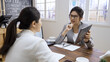 © PRPicturesProduction - Young female lawyer holding touch pad and talking something to client while sitting in modern cafe interior. Smart woman attorney using digital tablet for consultation with customer in coffee shop.