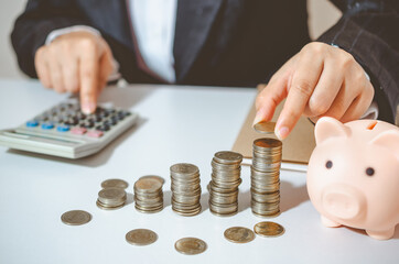 Closeup image businesswoman holding coins putting to stacking coins bank and calculating. concept saving money wealth for finance accounting.