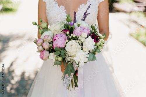 Wedding bouquet with white roses, peonies and green leaves. Bride in dress holds bouquet. Advert for wedding agency.
