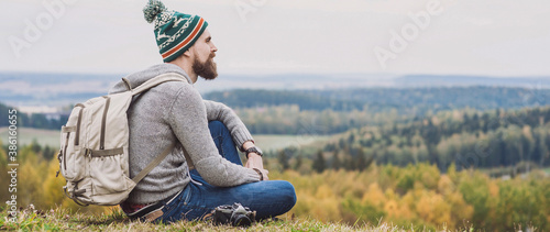 Fotografía Young man traveler sitting on top of the hill enjoy nature, Travel and active lifestyle concept, panoramic banner