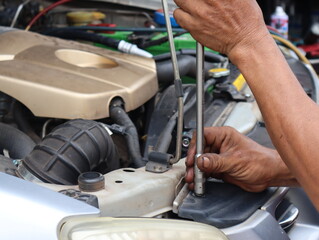 An engine mechanic in a car repair shop uses a  T-wrench to tighten the nut.