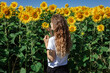 © Irida - A girl of European appearance with long blond hair stands in sunflowers.